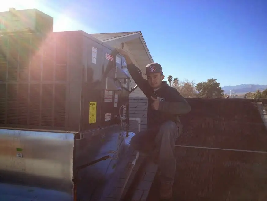 HVAC technician performing Air Duct Repair on a rooftop unit in Holland